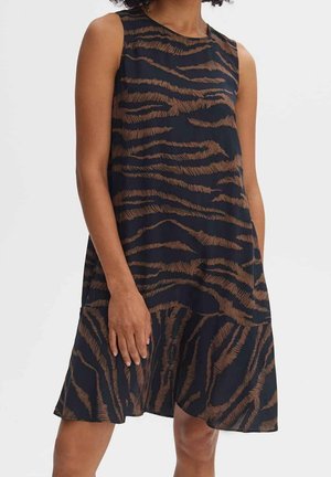 Czarna sukienka bez rękawów z brązowym wzorem przypominającym tygrysie paski, luźnym krojem i falbaną na dole, noszona przez stojącą osobę.