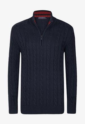 Marineblauer Kabelstrick-Pullover mit hohem Kragen und Viertel-Reißverschluss, der ein rot und marineblau gestreiftes Innenkragen-Design aufweist.