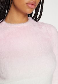 Różowy, puszysty sweter o miękkiej, pluszowej teksturze i zaokrąglonym dekolcie, z delikatną różnicą odcienia od kołnierzyka w dół.