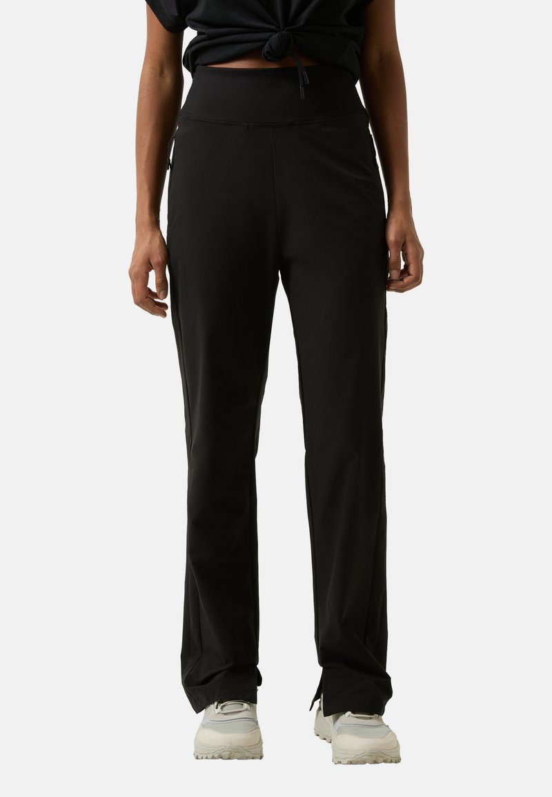 Schwarze Sporthose mit hohem Bund und lockerer Passform. Glattes Material, dezenter Glanz, Seitentaschen und elastische Details am Saum.