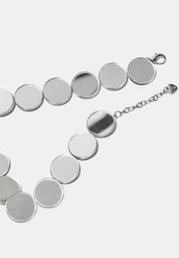 Sølv cirkulært vedhængs halskæde med polerede, reflekterende skiver, der har en metallisk lås og justerbar kædeledning i enden.