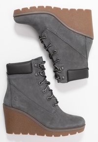 Stivaletti alla caviglia in pelle grigia con tacco a wedge, punta rotonda, sei occhielli con lacci scuri e suola in gomma marrone texturizzata.