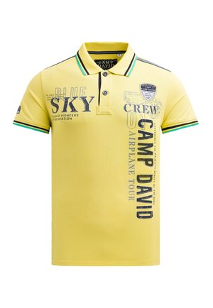 Yellow polo shirt with a collar, featuring black and green striped accents, printed text and graphics, textured fabric, and two buttons.