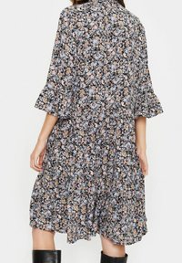 Blommig klänning med svart bakgrund, prydd med små rosa, blå och persikofärger blommor. Utsvängda ärmar och en avslappnad passform, knälång.