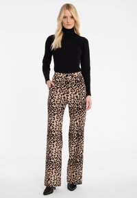 Zwart coltrui gecombineerd met hoge taille, wijde leg leopardprintbroek met een beige achtergrond en zwarte vlekken. Gladde textuur, geen zichtbare hardware.