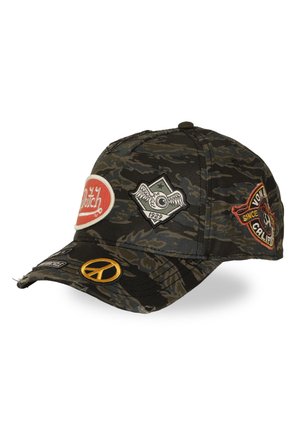 Casquette de baseball camouflage sombre avec plusieurs écussons brodés, y compris un ovale rouge, un œil avec des ailes, un symbole de paix et un écusson circulaire avec du texte.