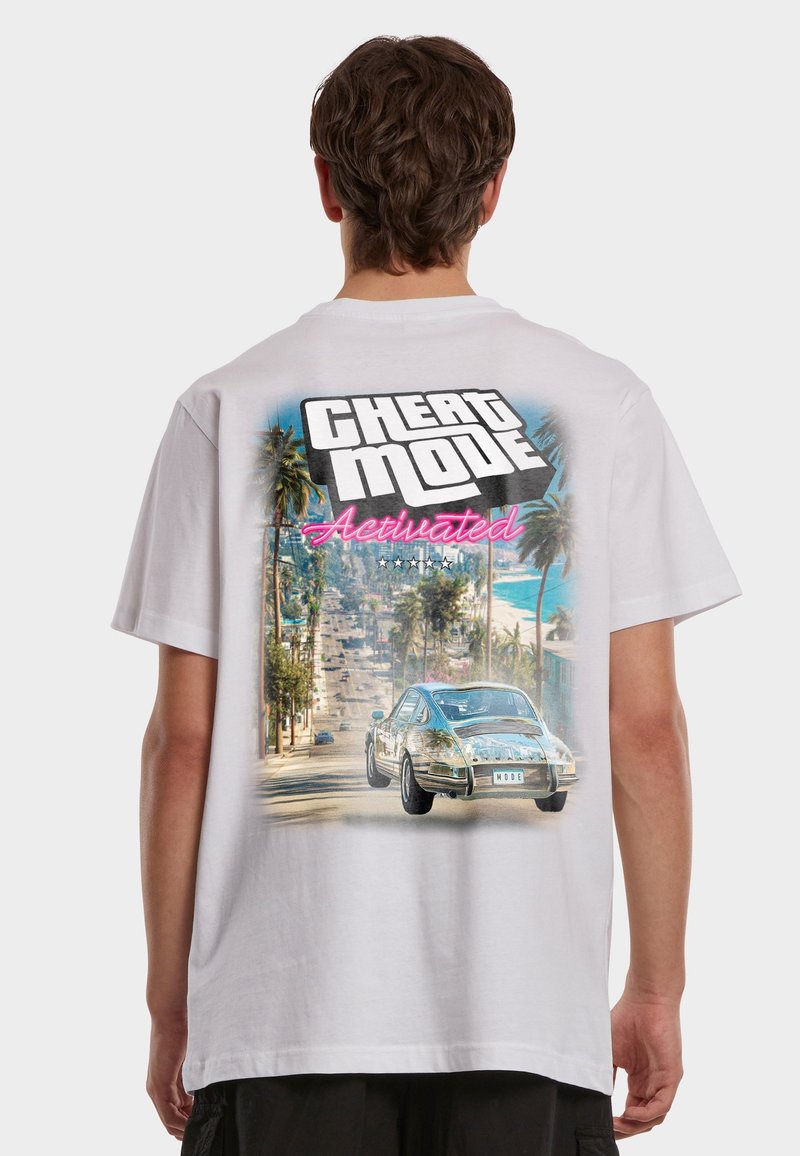 Person wearing white t-shirt with retro car driving down palm-lined street and text "Cheat Mode Activated" on the back.