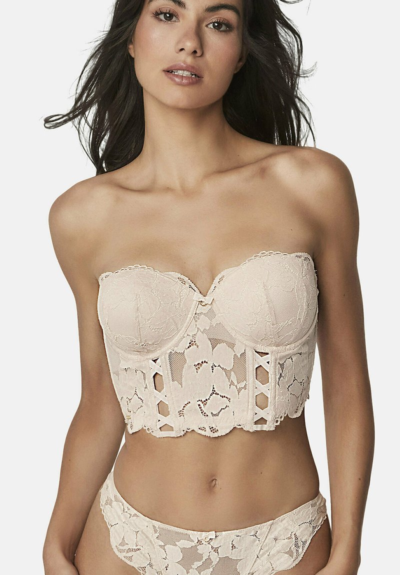 Bralette en dentelle beige sans bretelles avec motif floral, armatures pour la structure et détail croisé à l'avant. Accompagné d'un slip en dentelle assorti.