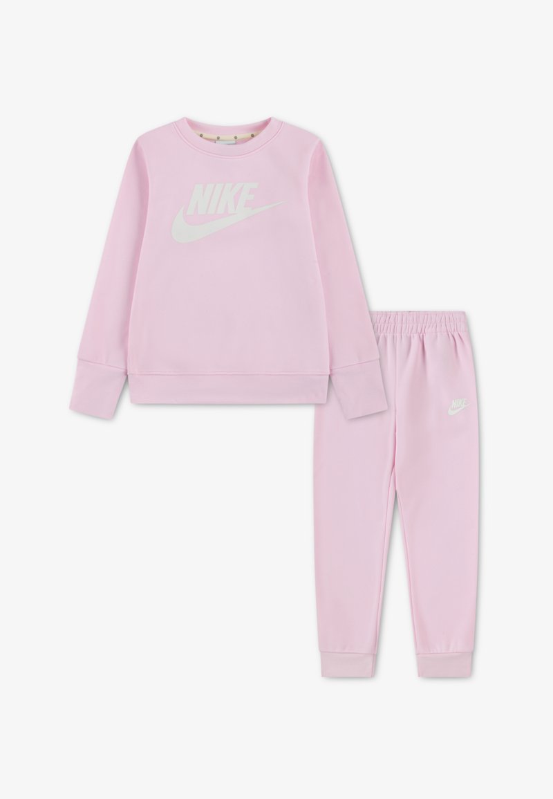 Różowa bluza i pasujące spodnie wykonane z miękkiego materiału. Bluza ma duże białe logo Nike; spodnie posiadają elastyczną talię.