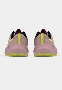 Zapatillas de running rosas con un acabado texturizado, acentos en negro y una franja amarilla en el talón. Suela gruesa con un patrón de agarre resistente.