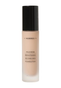 Base de maquillaje iluminadora de segunda piel Korres Wild Rose en un frasco de vidrio transparente con acabado mate beige y tapa negra. Texto en la botella en negro.