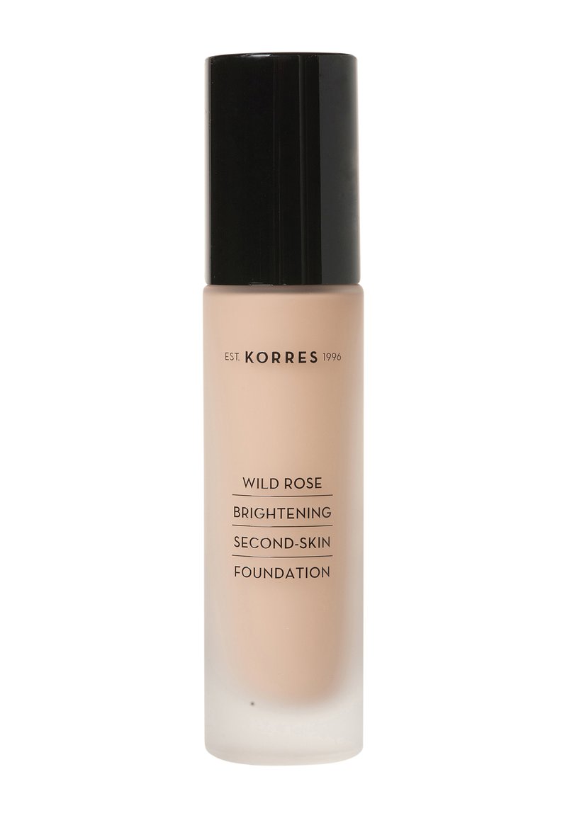 Base de maquillaje iluminadora de segunda piel Korres Wild Rose en un frasco de vidrio transparente con acabado mate beige y tapa negra. Texto en la botella en negro.