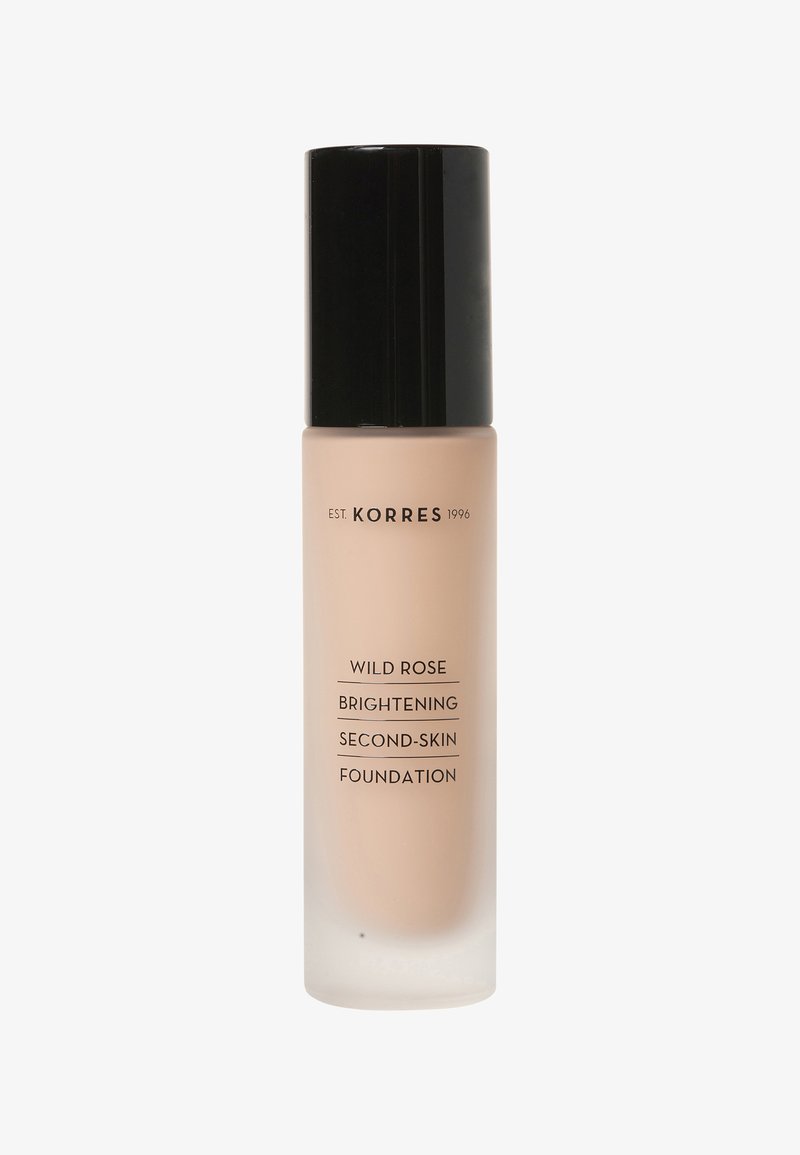 Korres Wild Rose Verhelderende Second-Skin Foundation in een heldere glazen fles met een matte beige afwerking en een zwarte dop. Tekst op de fles in het zwart.