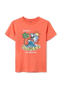 Camiseta de algodón color coral con un gráfico de un tiburón de dibujos animados, una ola y una palmera. El texto dice "El verano es increíble, sol, diversión y juego." Mangas cortas.