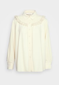 Cream long-sleeve blouse with button front and lace ruffle detail along the yoke and collar, relaxed fit.