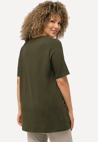 Olive zelené tričko s krátkým rukávem a volným střihem. Má jednoduchý design, měkkou texturu a rovný lem.