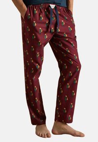 Kokvilnas pidžamas bikses tumši burgundijā ar atkārtotu lapsas grafiku. Iezīmē elastīgu jostasvietu ar savilcēju un sānu kabatām.