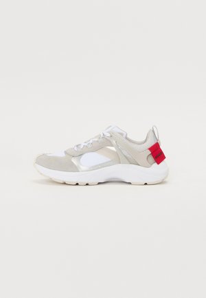 Sneakers with a light grey suede and mesh upper, white accents, and a red heel tab. Features a reflective detail and textured sole.