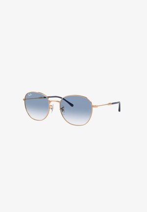 Occhiali da sole Ray-Ban con una montatura in metallo dorato, forma aviator, lenti blu sfumate e puntalini neri. Cuscinetti per il naso trasparenti e branding discreto.