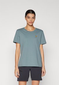 Light blue cotton t-shirt with short sleeves and a round neckline, featuring a small yellow and black surfboard graphic on the left chest.