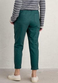 Groene katoenen broeken met een relaxed fit, met omgeslagen pijpen en achterzakken, in combinatie met crèmekleurige sneakers.