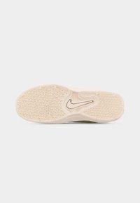 Σόλα μπεζ αθλητικού παπουτσιού Nike με υφή πέλματος και κεντρικό λογότυπο Nike swoosh στην περιοχή της καμάρας.