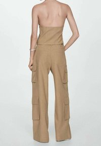 Beige cargobroek met wijde pijpen, meerdere zijzakken en een gladde textuur, ontworpen voor een comfortabele pasvorm.