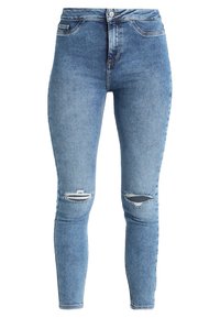 Jeans ajustados en denim de color azul claro, con una cintura alta, roturas desgastadas en las rodillas y un diseño clásico de cinco bolsillos con cierre de botón metálico.