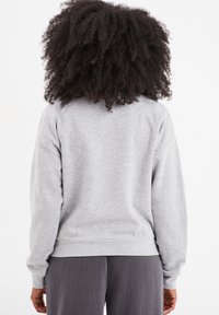 Felpa in misto cotone grigia con maniche lunghe, polsini a costine e orlo arrotondato. Texture liscia e vestibilità rilassata, progettata per il comfort.