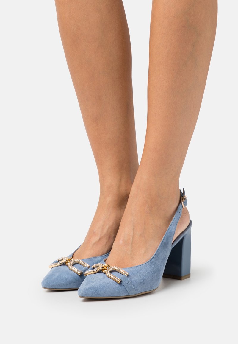 Vaaleansinisiä mokkanahkaisia slingback-korkokenkiä, joissa on teräväkärkinen muoto ja paksu korko. Edessä koristeellinen kultainen ja strassikoruinen rusetti.