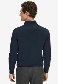 Laivaston värinen vetoketjullinen neulepaita, jossa on korkea kaulus, teksturoitu neulemateriaali ja pitkät hihat. Ominaisuuksia ovat tasavärinen pinta ja vähäiset ompelusaumat.