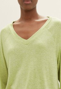 V-Ausschnitt-Pullover in Hellgrün, aus weichem, strukturiertem Stoff. Verfügt über Raglanärmel und eine lockere Passform, geeignet für legere Anlässe.