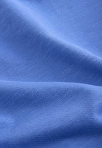 Mehka modra tkanina z fino rebrasto teksturo in vidnimi gubami, ki poudarjajo gladke in rahlo dvignjene detajle tkanja.