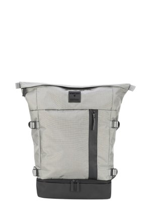 Zaino in tessuto grigio con design a risvolto, dotato di una tasca frontale, dettagli in cerniera nera e cinturini laterali regolabili per la chiusura.