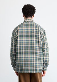Skjorte med tern i navy, grøn og beige farver, lange ærmer, almindelig krave og en afslappet pasform med knapmanchetter.
