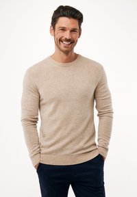 Maglione beige realizzato in materiale morbido, con scollatura rotonda e maniche lunghe. La texture è liscia con un sottile motivo a maglia.