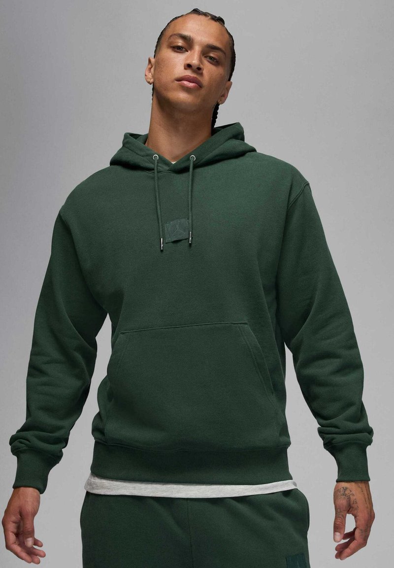 Ciemnozielona bluza z kapturem wykonana z miękkiego materiału. Posiada kieszeń z przodu i regulowane sznurki. Pod spodem szara koszulka.