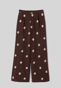 Pantalon marron à jambes larges avec broderie blanche en forme de soleil répartie uniformément sur le tissu sur un fond uni.