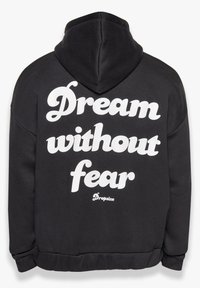 Schwarzer Kapuzenpullover mit gefütterter Kapuze, elastischen Bündchen und einem großen weißen Druck auf dem Rücken, der "Träume ohne Angst" lautet, mit dem Markennamen darunter.