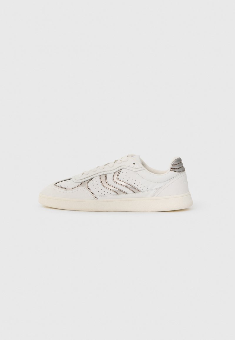 Vit lågtoppsneaker med beige sula, perforerade sidopaneler, dekorativ sömnad och grå accent på hälfliken placerad på en enkel bakgrund.