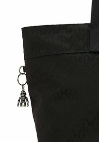 Czarna torba tote z materiału z wzorem w diamenty, z metalowym breloczkiem w kształcie małej czarnej postaci oraz mocnymi czarnymi ramiączkami.