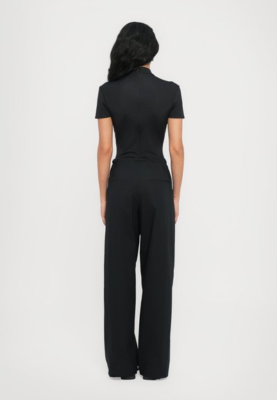 Black two-piece outfit featuring a fitted short-sleeve top and wide-leg pants, both in a smooth, stretchy fabric with minimal details.