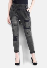 Grå denim tapered byxor med sydda lappar, framveck, fyraknapps midja och pärlbroderi längs fållarna.