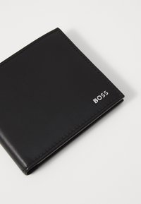 Portafoglio in pelle nera con una finitura liscia, dotato di bordi cuciti e un logo "BOSS" in argento nell'angolo in basso a destra.