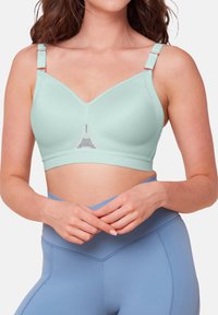 Lys myntegrønn sport-bh med sømløst design, justerbare stropper og mesh-detalj i midten. Kombinert med høyhalsede blå leggings.