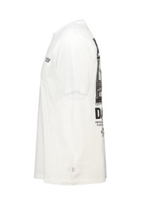 Camiseta blanca de algodón. Presenta un estampado gráfico lateral en negro que representa líneas arquitectónicas y texto. Mangas cortas y cuello redondo.