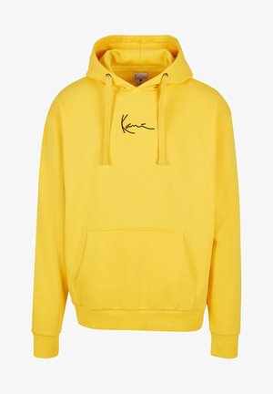Sweat à capuche jaune avec poche avant et cordons, featuring un petit logo noir en cursive centré sur la poitrine.