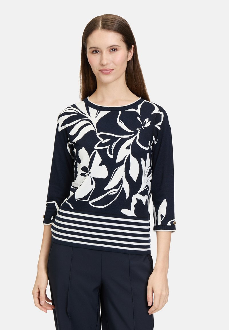 Marineblauw top met een wit bloempatroon en gestreepte onderkant. Voorzien van 3/4 mouwen met knoopaccenten en een ronde halslijn. Zachte stoffen textuur.