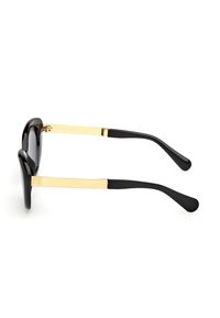 Gafas de sol negras con un acabado brillante, que presentan acentos metálicos dorados en las patillas y un diseño suave y curvado.