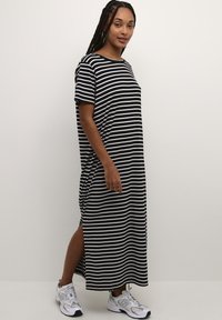 Black and white striped maxi dress with short sleeves, round neckline, and side slits. Worn with gray sneakers.